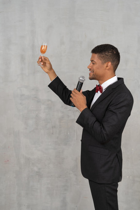 Homem com roupa formal, levantando um copo e propondo um brinde