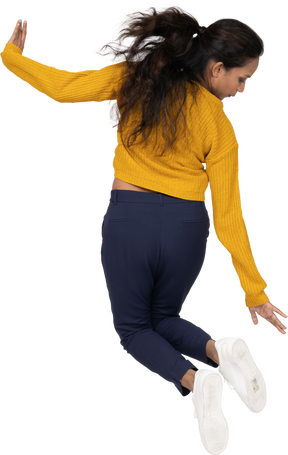 Rear view of a girl in casual clothes jumping