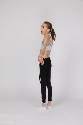 Side view of a teen girl in sportswear raising hand and arguing