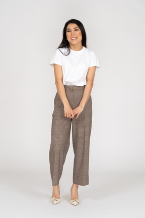 Front view of a shy smiling young lady in breeches and t-shirt holding hands together