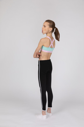 Side view of a teen girl in sportswear raising hand and arguing