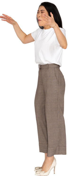 Three-quarter view of a naughty young lady in breeches and t-shirt raising her hands