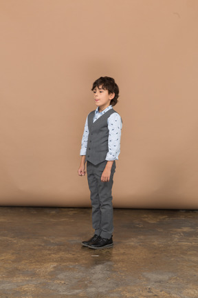 Garçon mignon en costume gris immobile