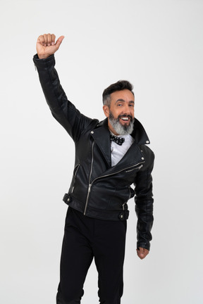 Hombre maduro satisfecho, vestido con chaqueta y levantando su mano.