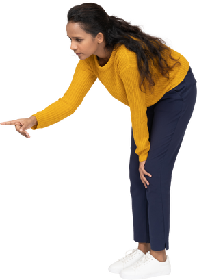 Side view of a girl in casual clothes bending down and pointing with finger