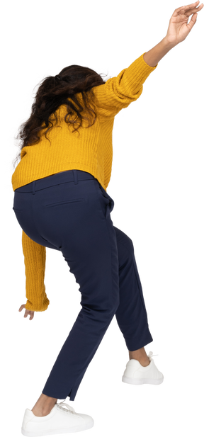 Rear view of a girl in casual clothes posing on one leg with outstretched arms