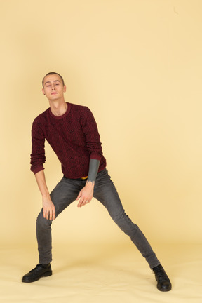 Front view of a young man in red pullover stretching his leg