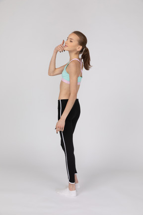 Side view of a teen girl in sportswear raising hand and arguing