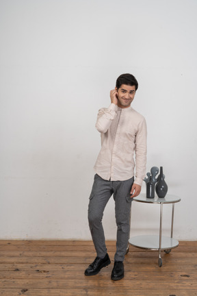 Front view of a man in casual clothes touching ear