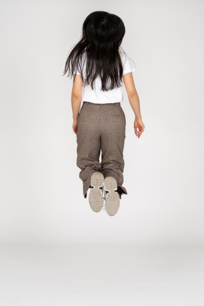 Back view of a jumping young lady in breeches and t-shirt bending knees
