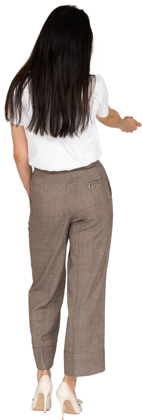 Three-quarter back view of a young lady in breeches and t-shirt outstretching her hand