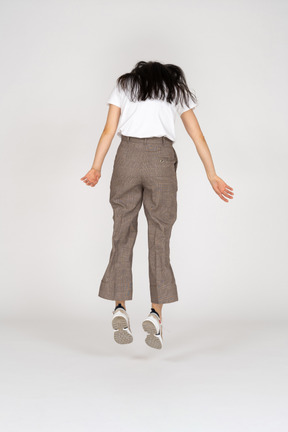 Back view of a jumping young lady in breeches and t-shirt looking down