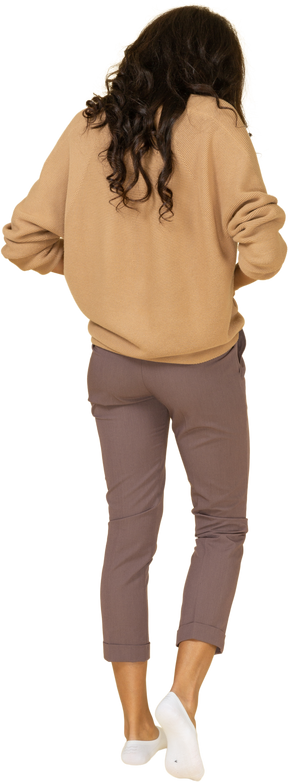 Three-back back view of a dark-skinned young female zipping up her pants