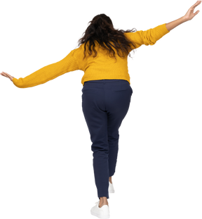 Rear view of a girl in casual clothes posing with outstretched arms