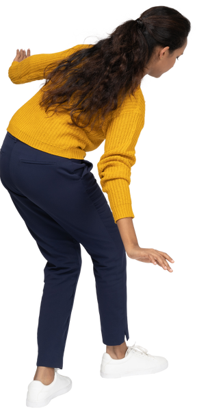 Rear view of a girl in casual clothes posing on one leg with outstretched arms
