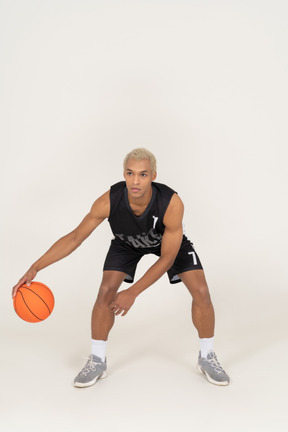 Front view of a young male basketball player doing dribbling