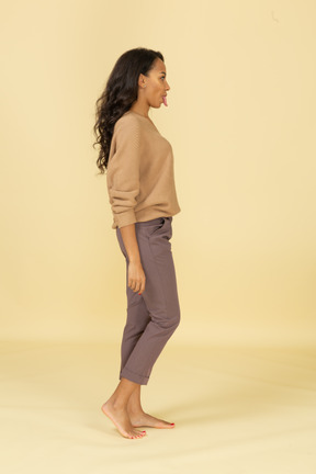 Vista lateral de uma jovem mulher com roupas casuais, mostrando a língua