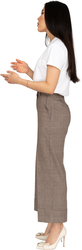 Side view of a gesticulating young lady in breeches and t-shirt explaining something