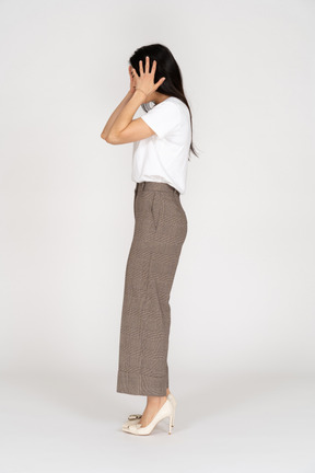 Vista lateral de uma jovem senhora de calça e camiseta tocando a cabeça dela